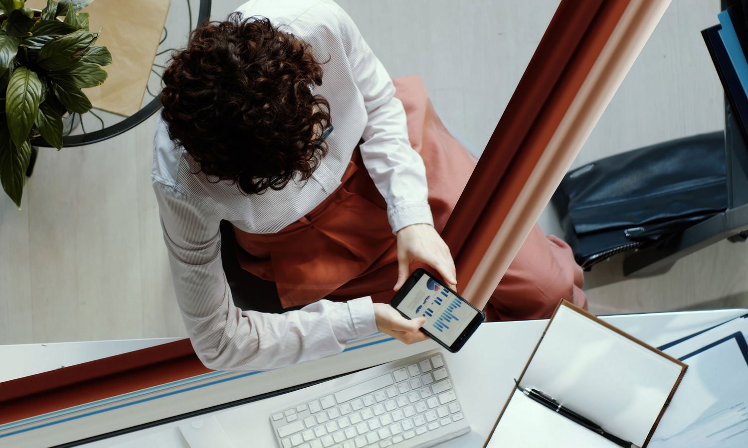 Businesswoman reviewing charts on her phone, the edge of the device stretches beyond the frame 