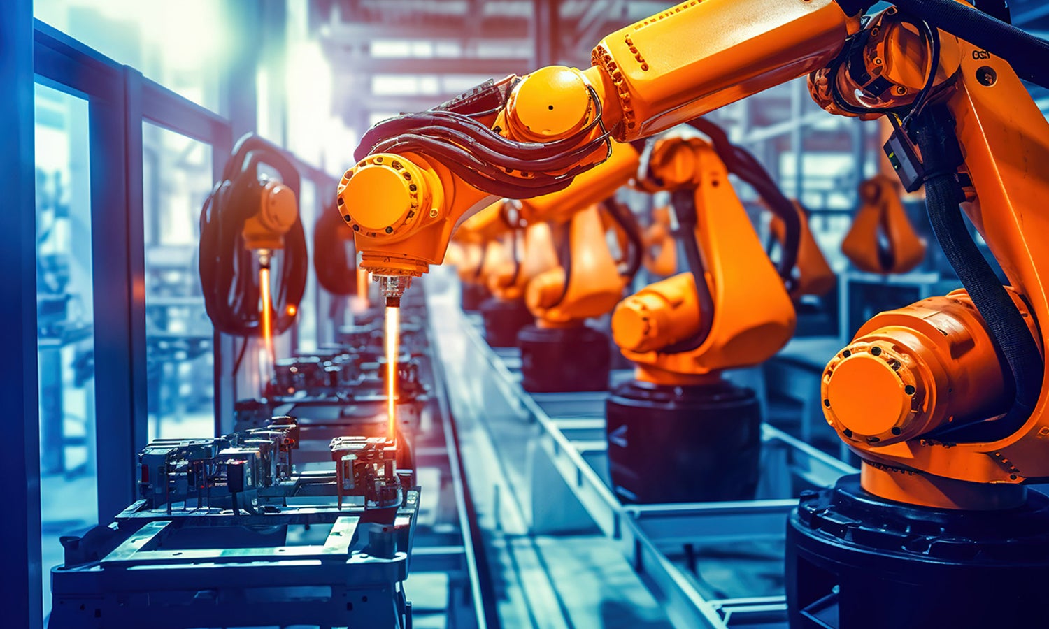 Orange robotic arm welding on an assembly line